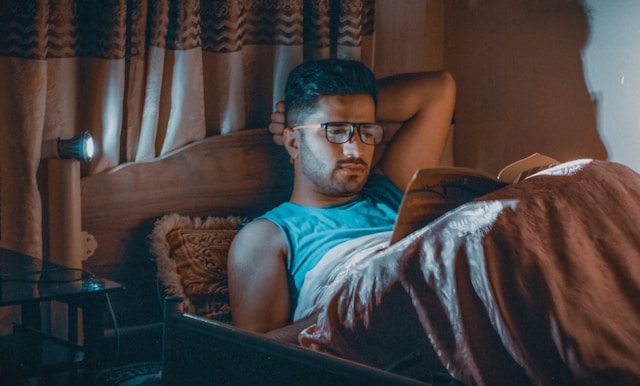 Person reading as part of their bedtime routine for better sleep in warm dim lighting