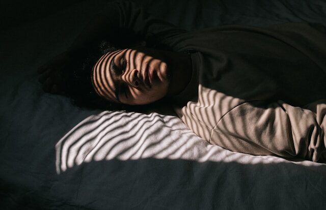 Person learning how to fall asleep with anxiety using breathing techniques in a peaceful bedroom