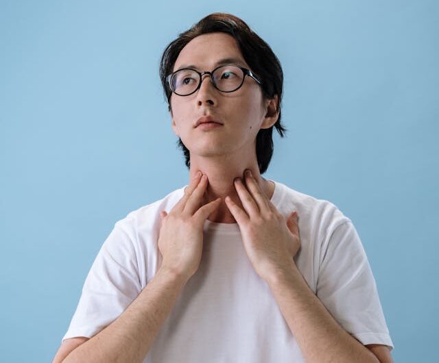 Person holding throat in pain looking for what kills a sore throat fast overnight remedies