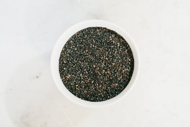 black seed oil bottle with Nigella sativa seeds on wooden table natural supplement