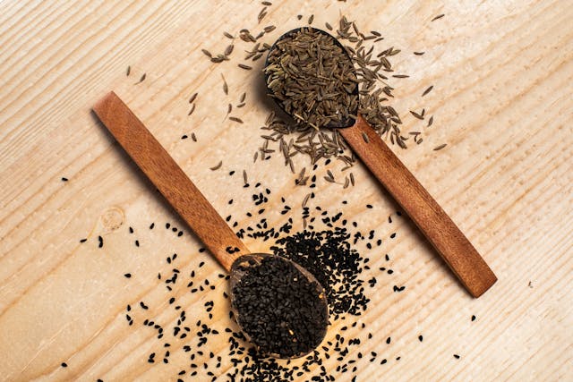 black seed oil bottle with Nigella sativa seeds on wooden table natural supplement