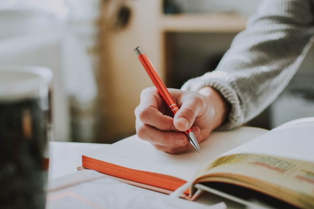person practicing critical thinking exercises journaling at desk with notebook and pen