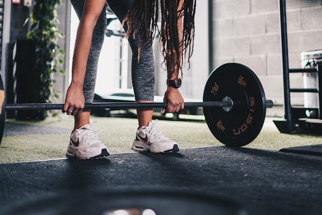 woman performing glute exercises hip thrust with barbell on gym bench