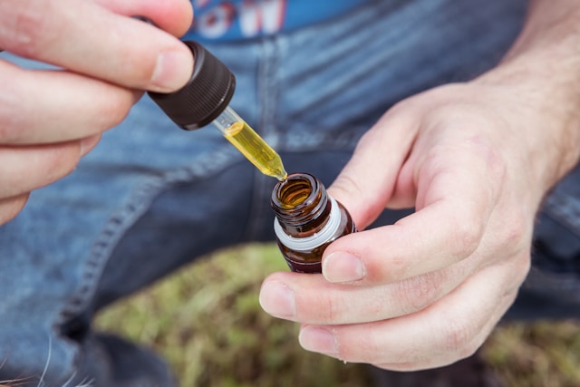 person measuring how much cbd oil should i take with dropper bottle