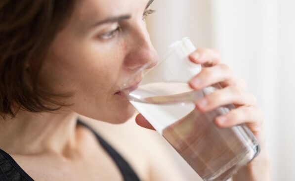 woman practicing intermittent fasting for beginners with a glass of water at sunrise