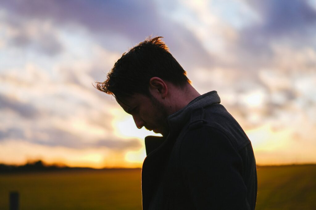 man sitting thoughtfully alone outdoors representing men's mental health month awareness and reflection