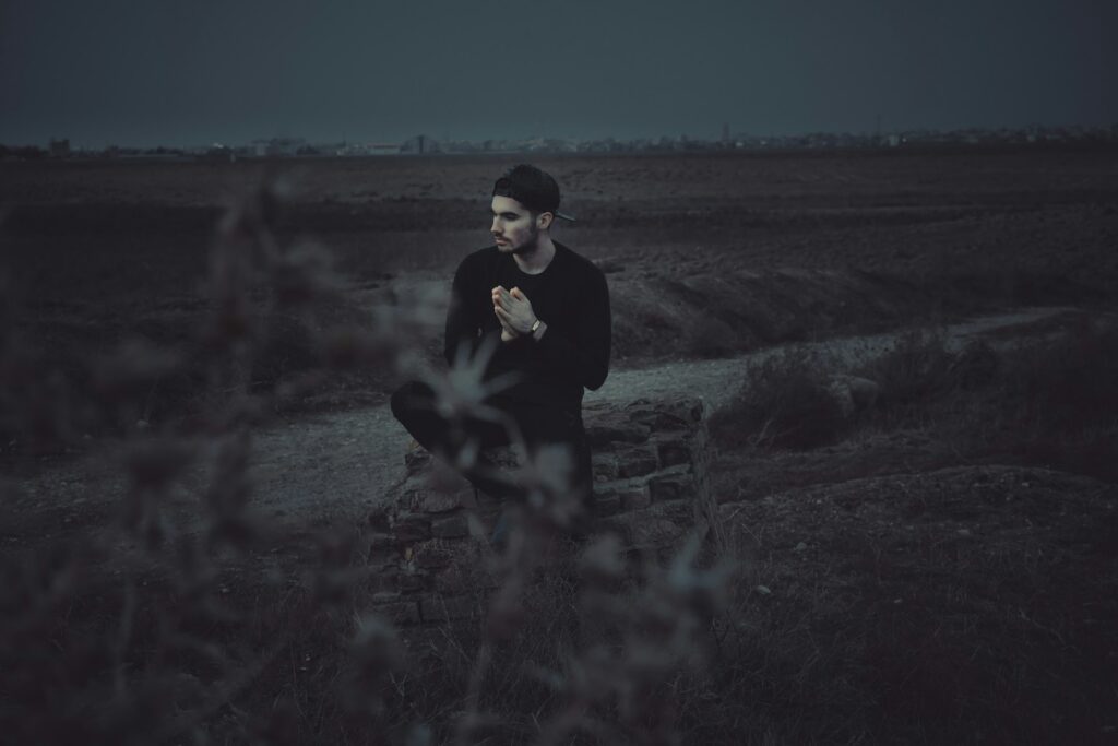 man sitting thoughtfully alone outdoors representing mens mental health month awareness
